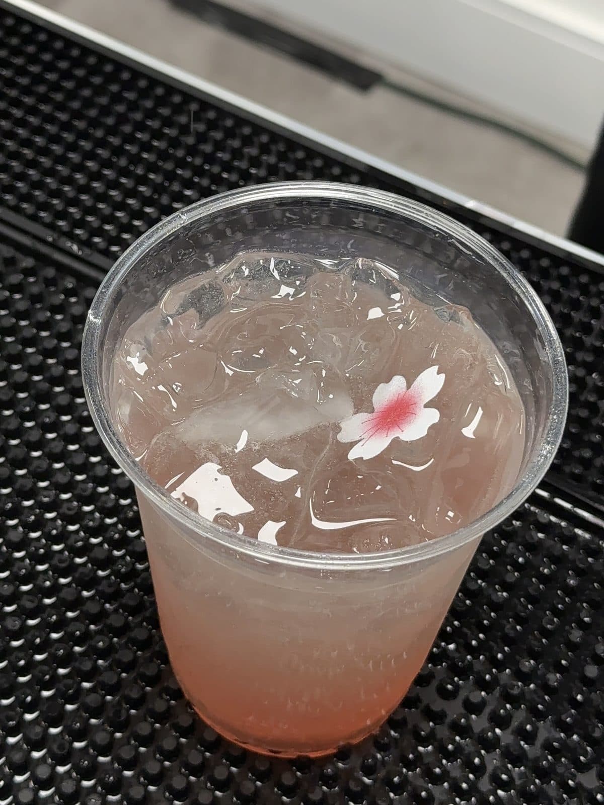 A pink cocktail with a flower garnish on the bar mat