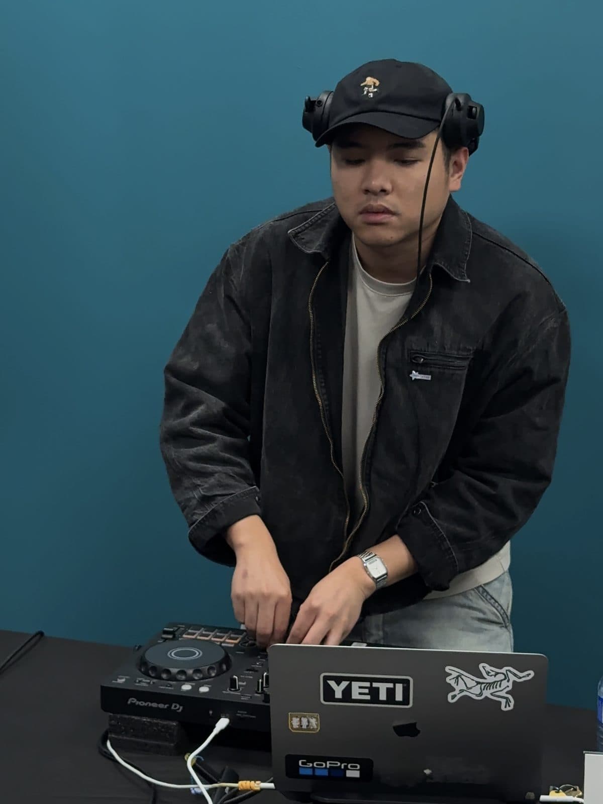 The DJ at the decks against the teal wall