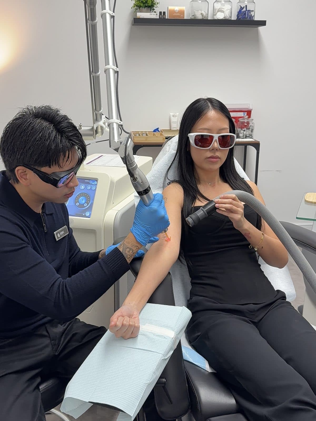 A technician giving a laser demonstration on a team member's arm, both wearing protective glasses