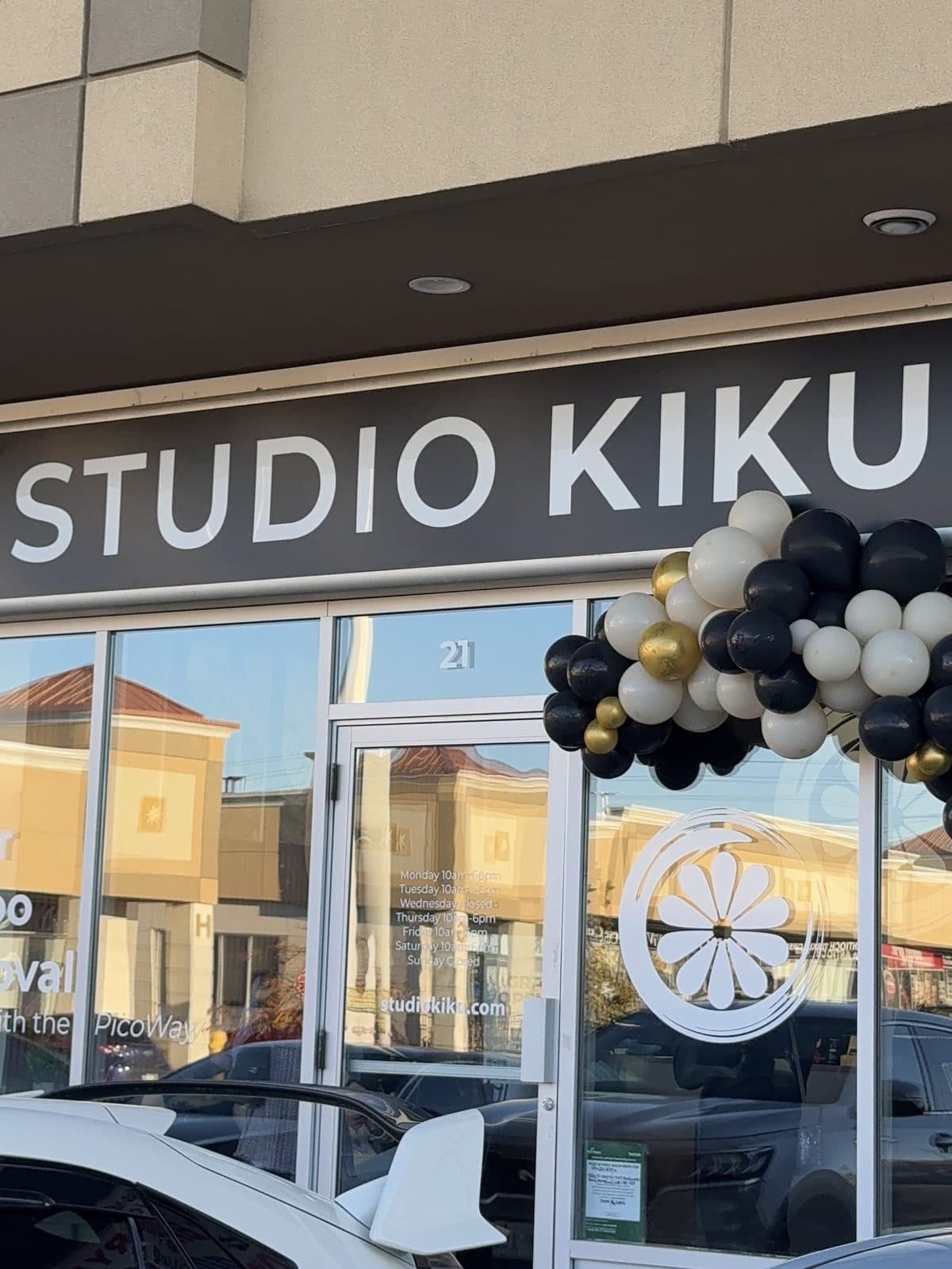 The Studio Kiku Vaughan storefront at Unit 21 with a black, white and gold balloon arch beside the door