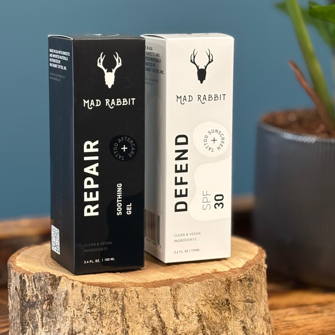Mad Rabbit Repair Soothing Gel and Defend SPF 30 Sunscreen boxes displayed on a wooden stump