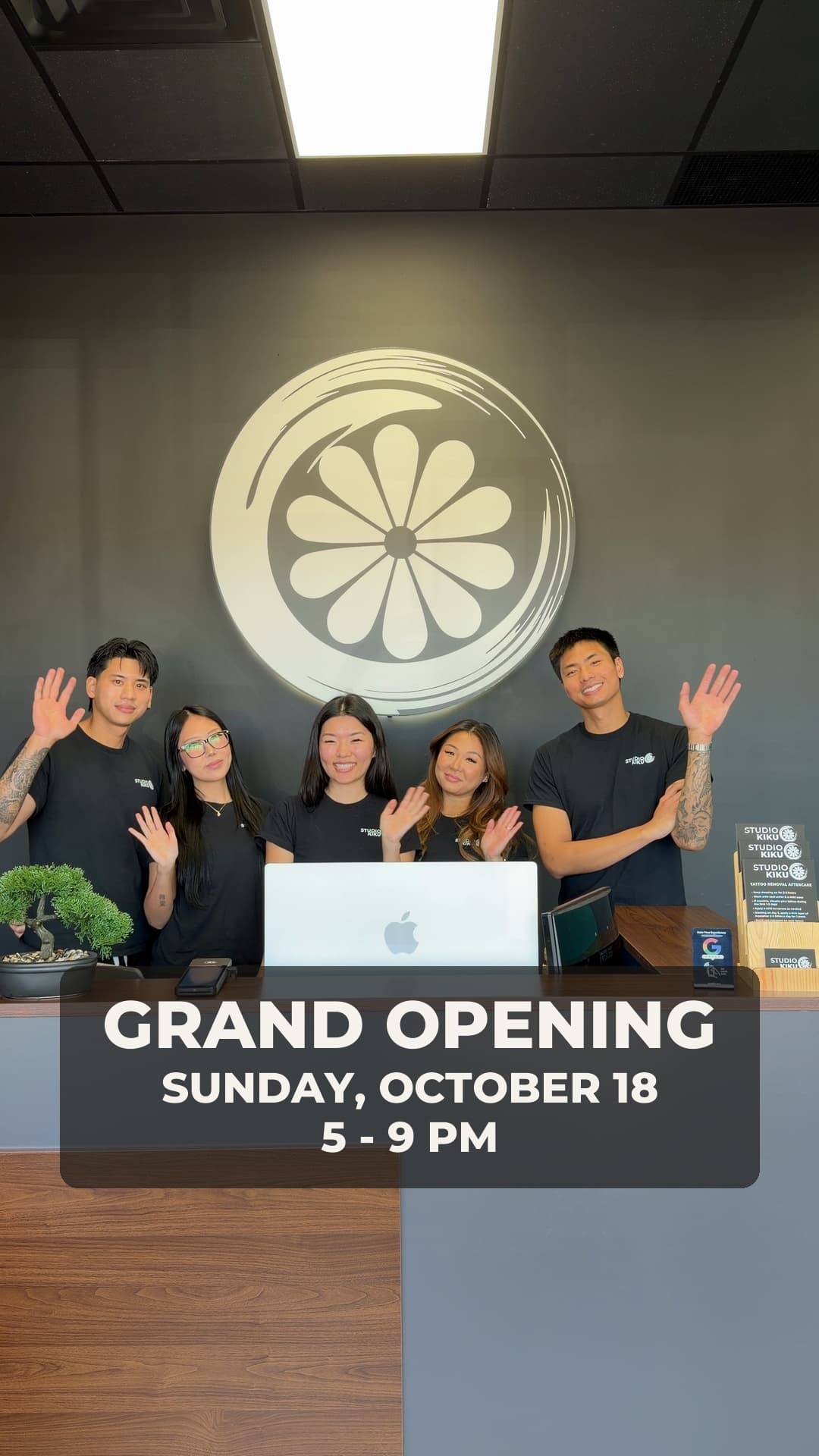 The Studio Kiku Vaughan team waving from behind the front desk under the Kiku logo, with the grand opening date printed across the photo