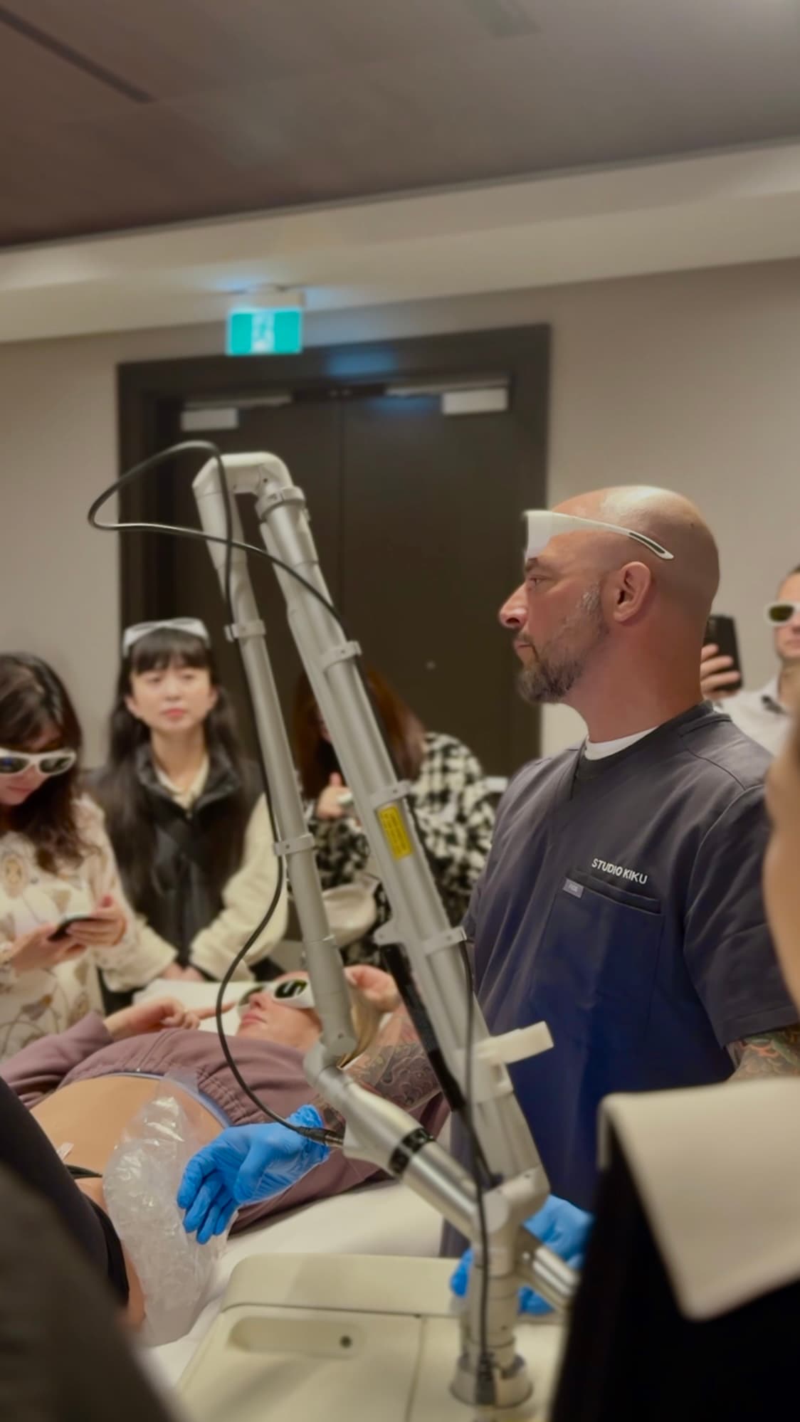 Billy DeCola leading an in-person laser tattoo removal training session at Studio Kiku, treating a live model while students observe